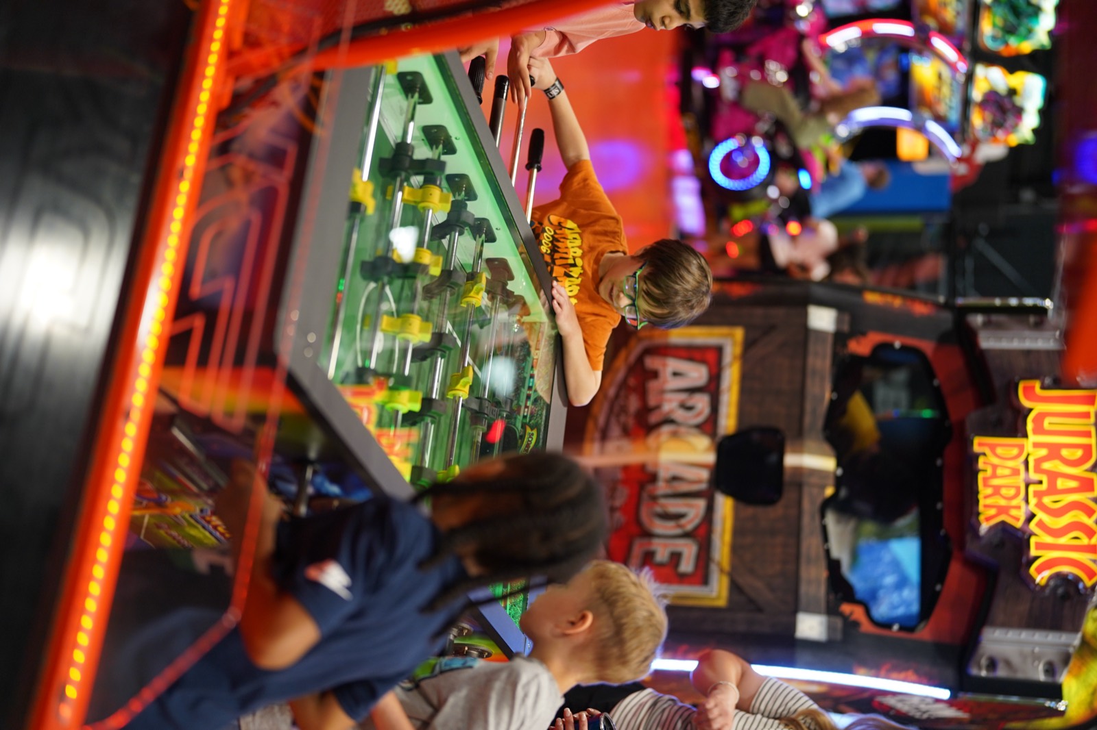 Kids playing a head-to-head foosball table at the SkyTag arcade lounge in Montreal